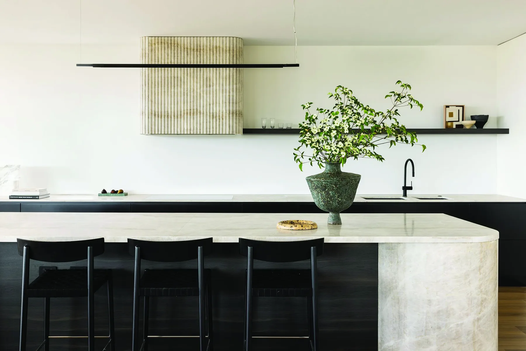Mosman 02 &mdash; kitchen with curved stone island, fluted rangehood and black stools