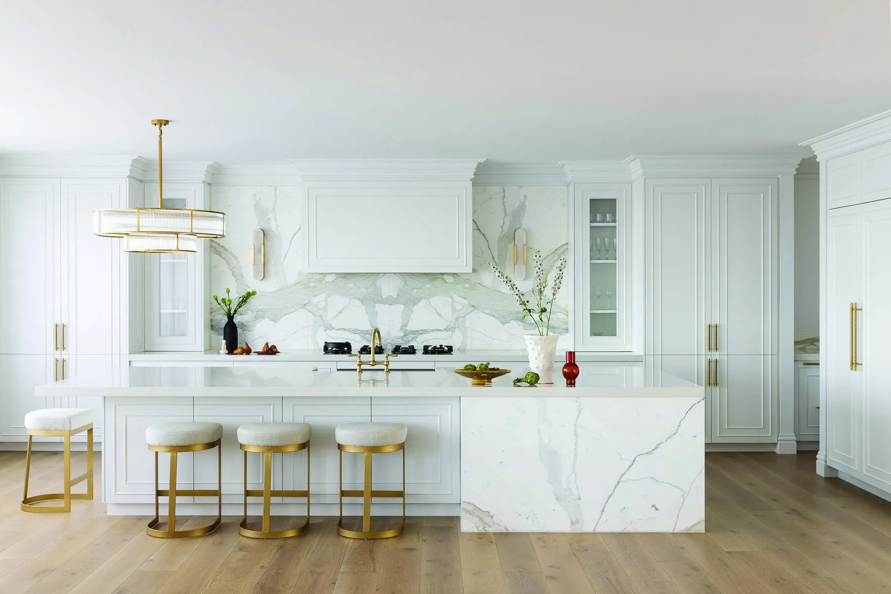 Elanora &mdash; white kitchen with marble waterfall island and brass-framed stools