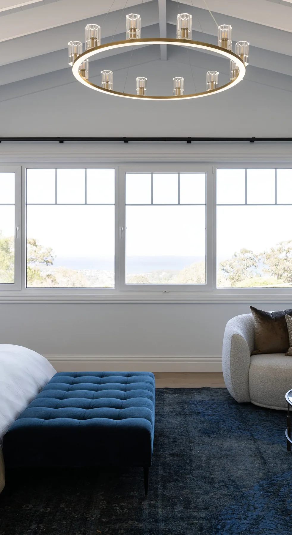 Elanora &mdash; main bedroom with brass chandelier and windows to the coastline