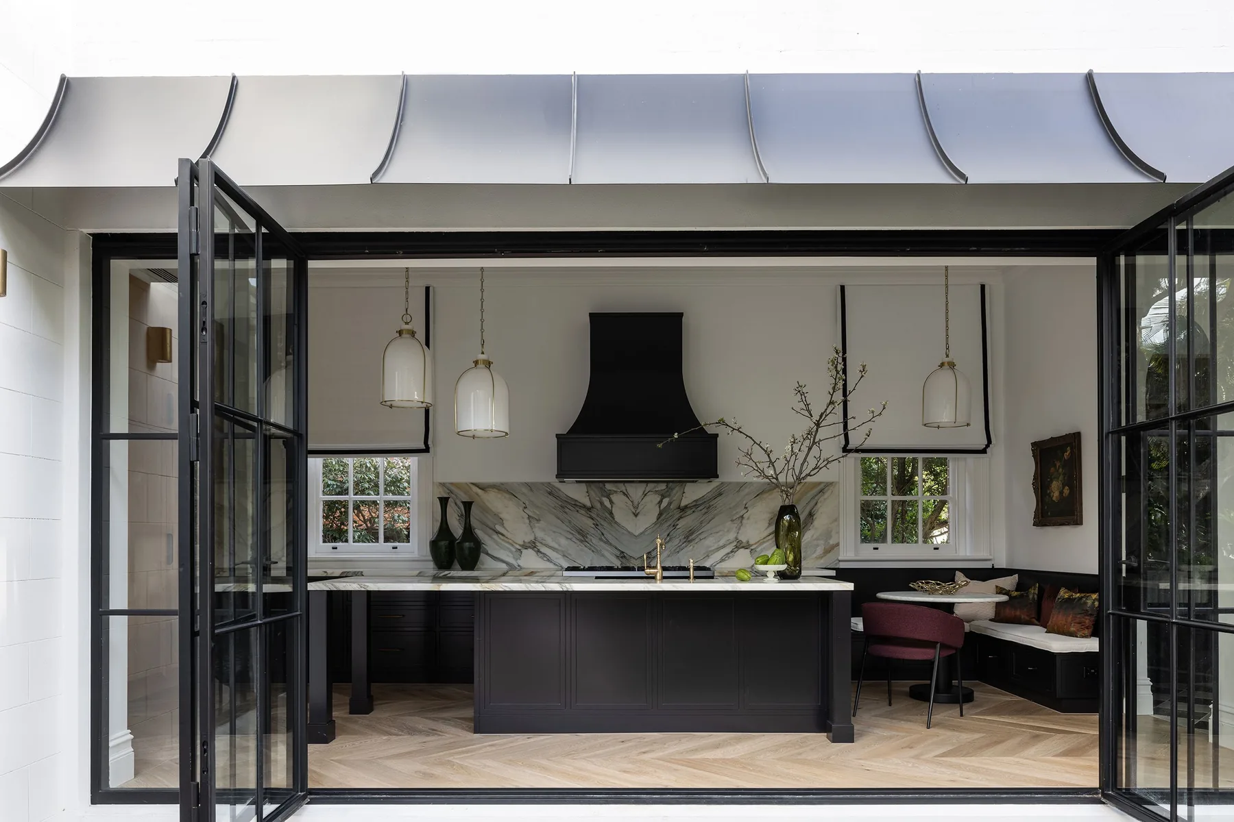 Mosman 01 &mdash; kitchen opening through steel-framed doors, with black rangehood and stone splashback