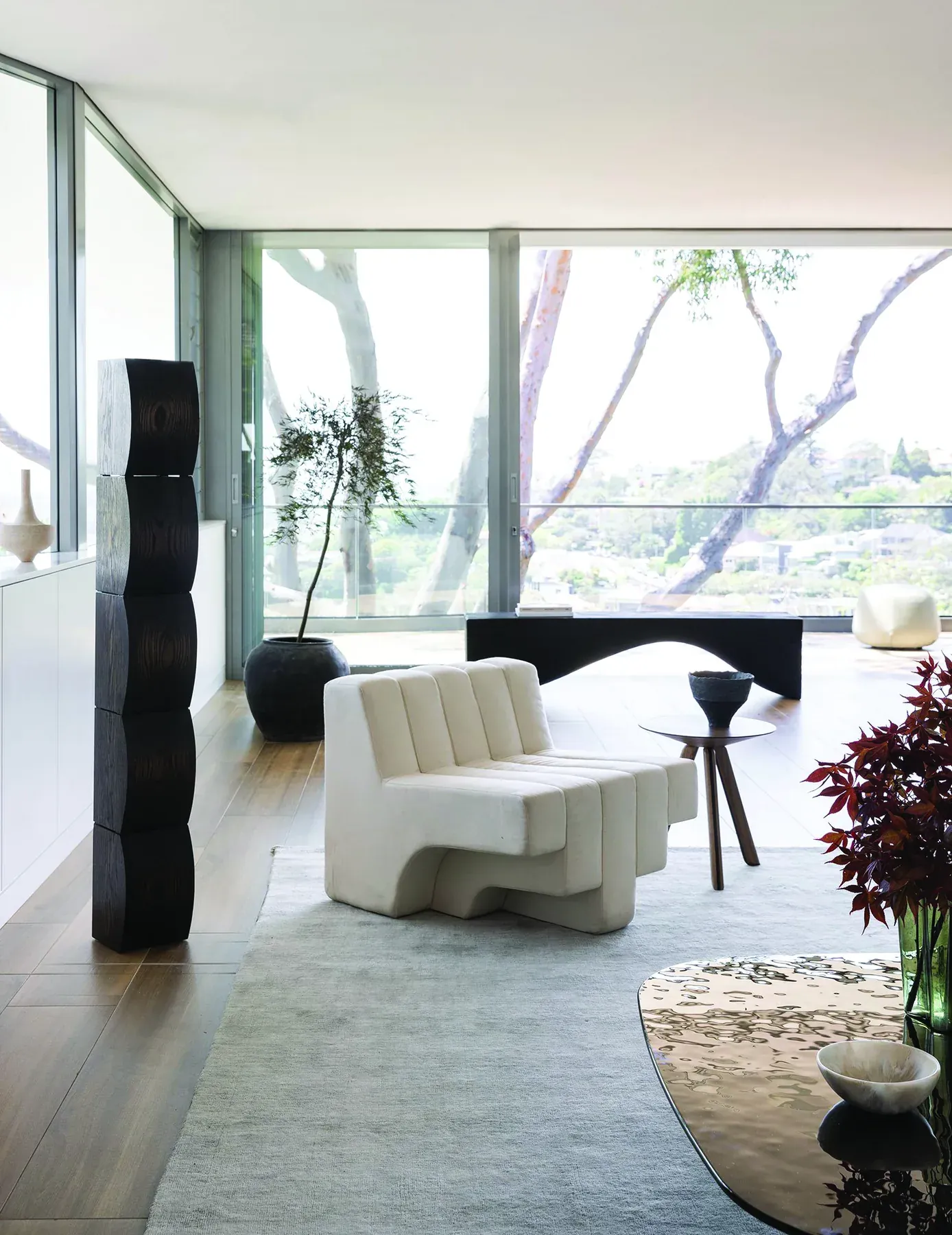 Mosman 02 &mdash; sculptural sofa and carved black timber totems before floor-to-ceiling windows