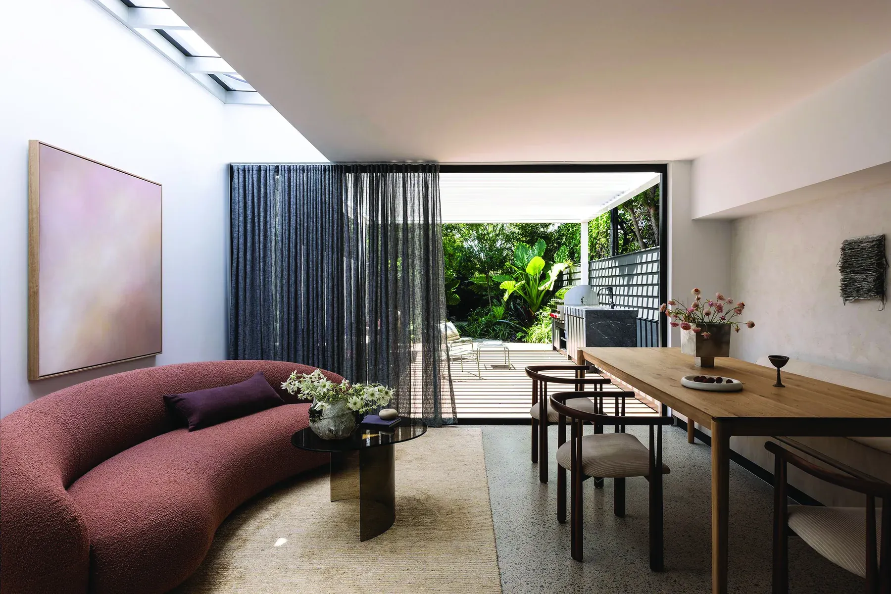 North Sydney, Lower North Shore &mdash; living and dining area with burgundy curved sofa, timber table and courtyard beyond