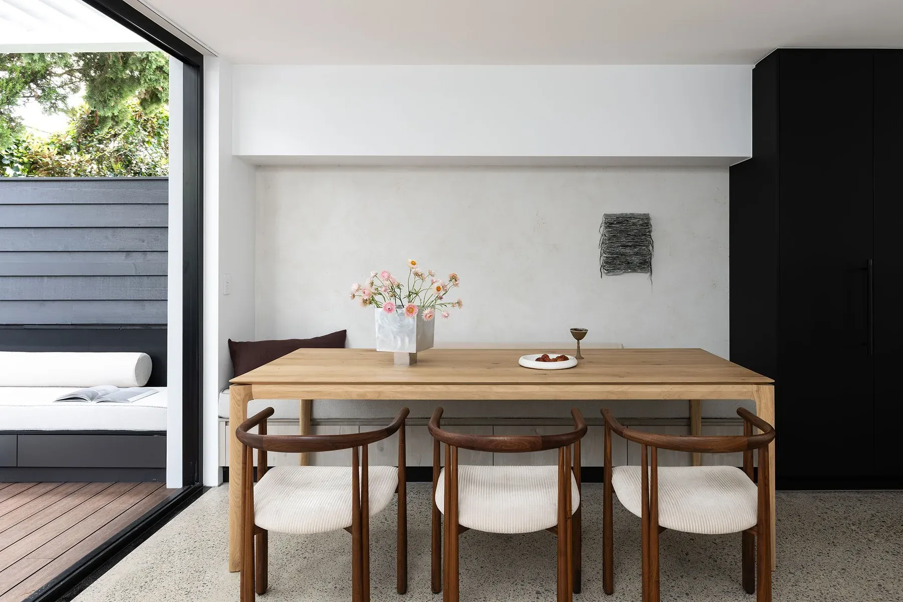 North Sydney &mdash; timber dining table with sculptural chairs beside black cabinetry