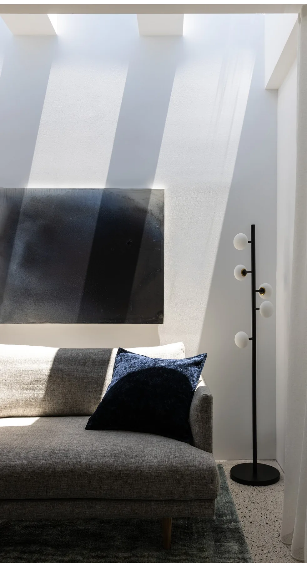 North Sydney &mdash; grey sofa with navy cushion and dark abstract artwork in a light-filled corner