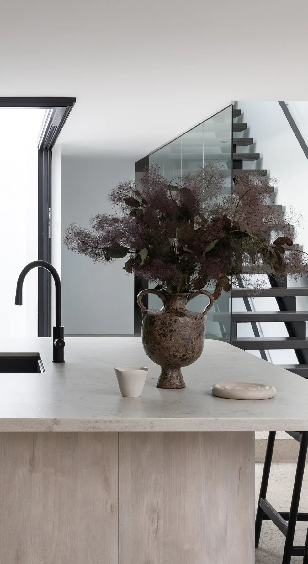 North Sydney &mdash; kitchen island with stone-look top, black tap and view to the staircase