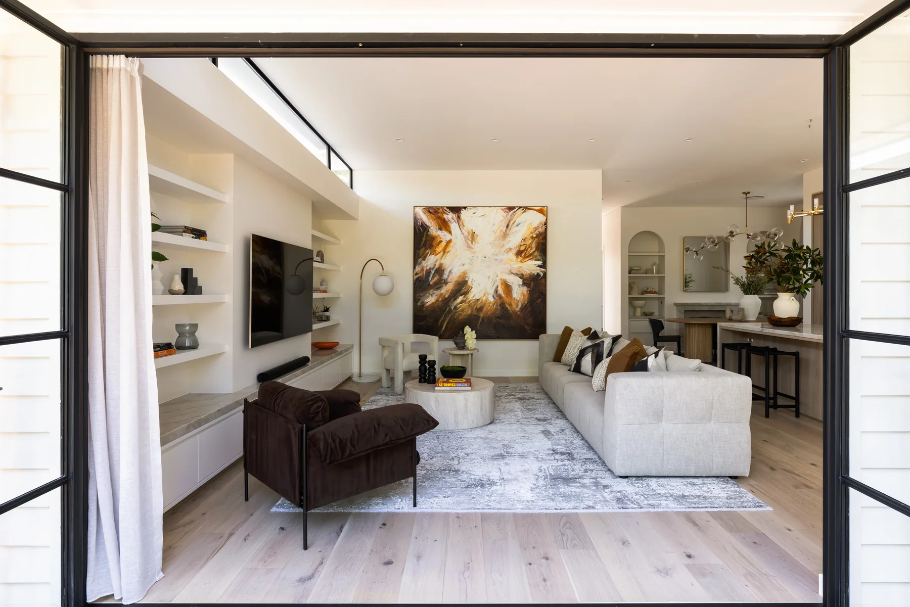 Russell Lea, Inner West &mdash; living room seen through steel-framed doors, with a large abstract artwork and cream sofa