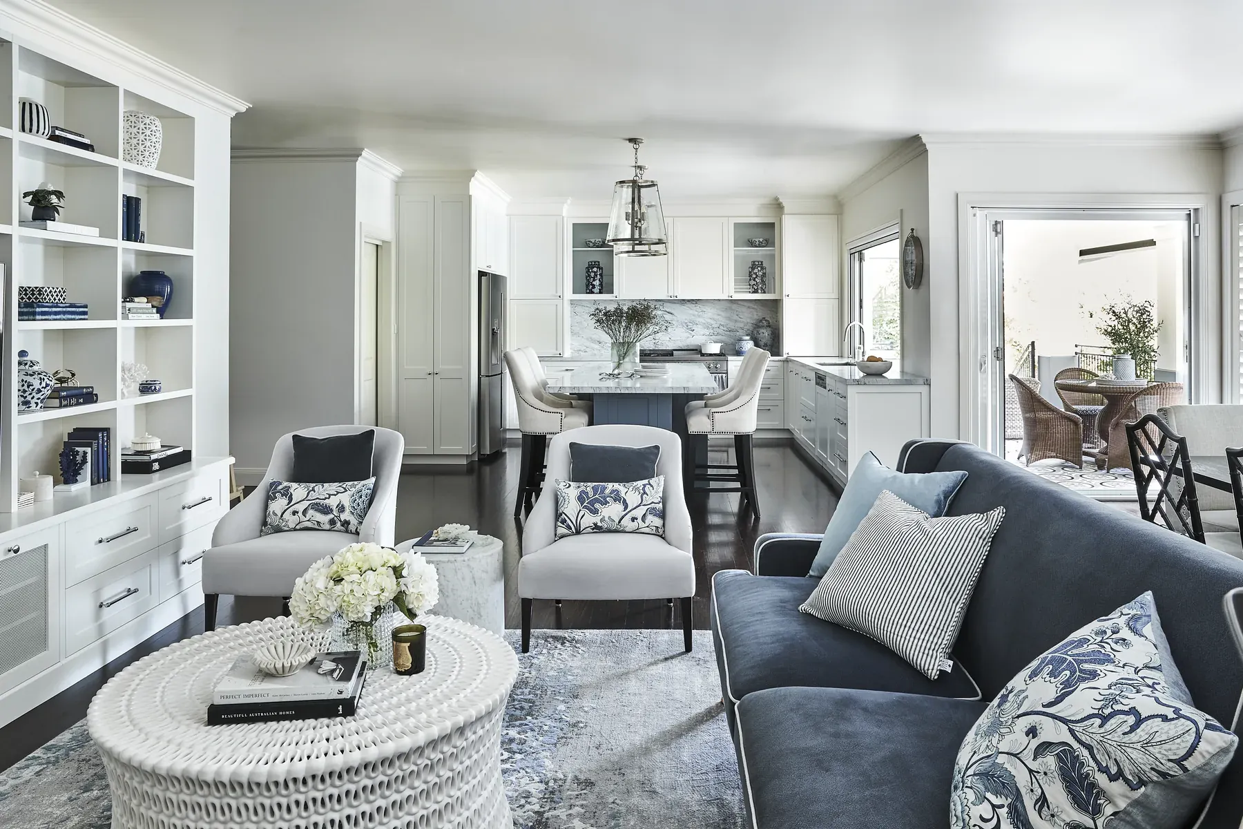 Wahroonga &mdash; open living area with navy velvet sofa, woven white coffee table and built-in shelving