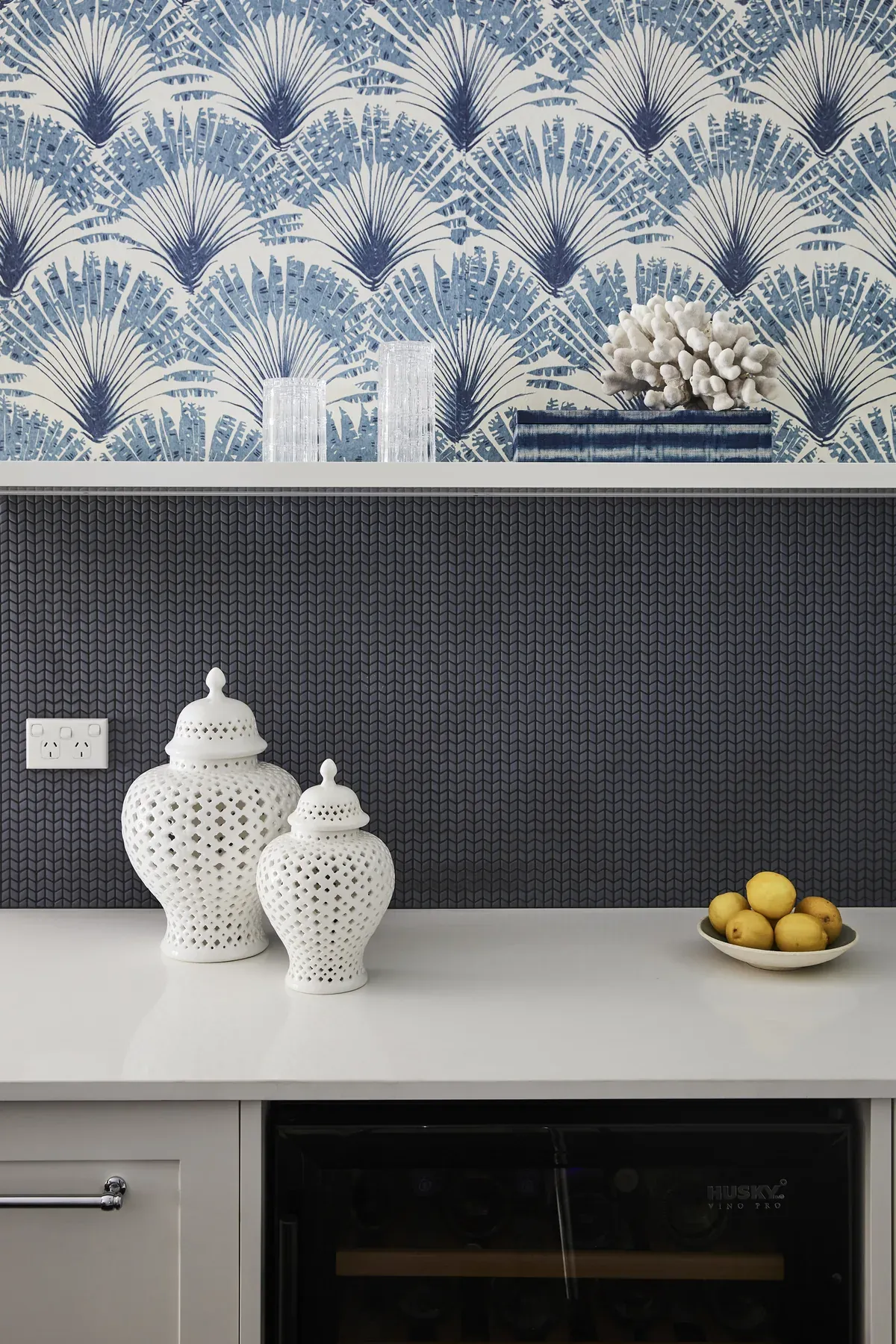 Wahroonga &mdash; blue palm wallpaper above a navy tiled splashback and white ginger jars